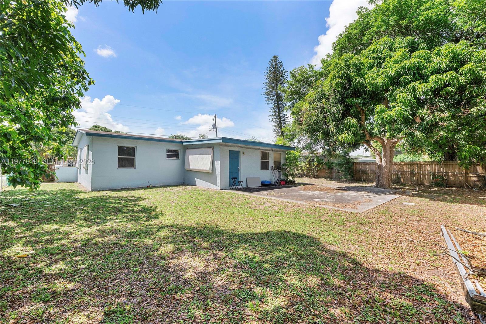 The exterior of a light blue house features a concrete patio and a large tree — 800 NW 33rd Ave, Lauderhill FL 33311, LAUDERHILL, FL