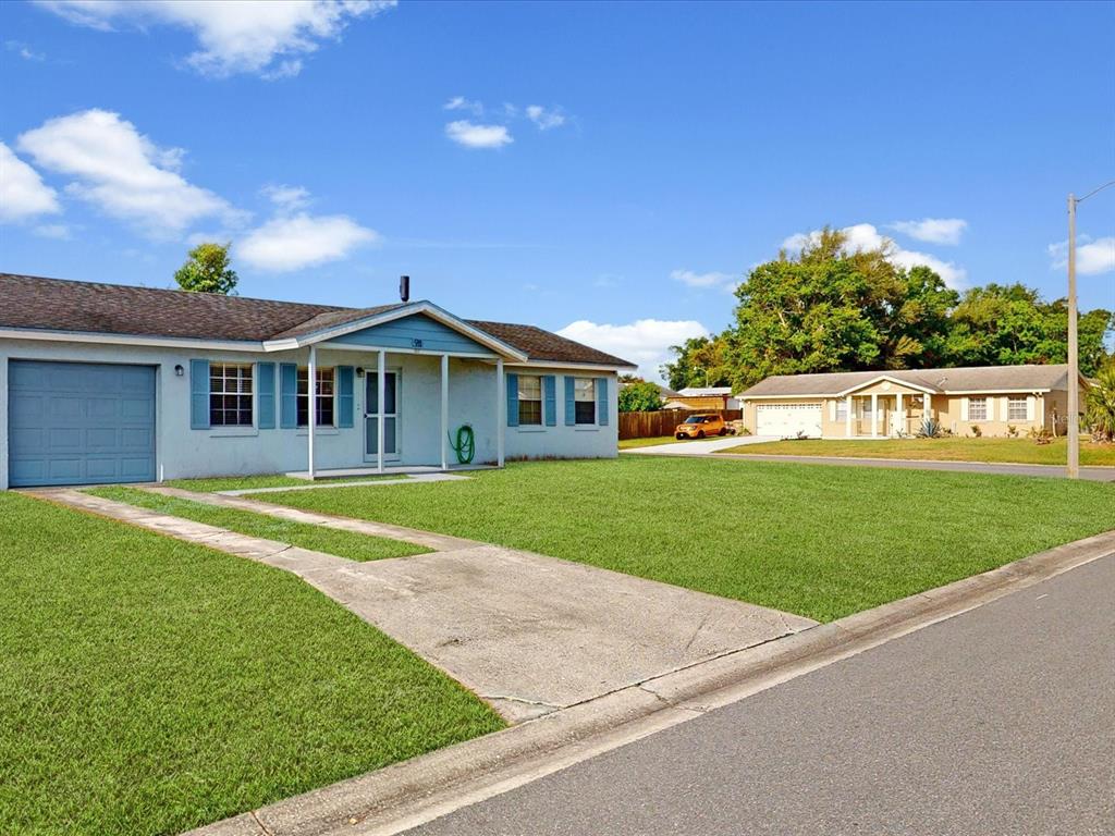 A single-story house with a blue garage door, light-colored siding, and a front lawn — 98 PINATA COURT, KISSIMMEE, FL