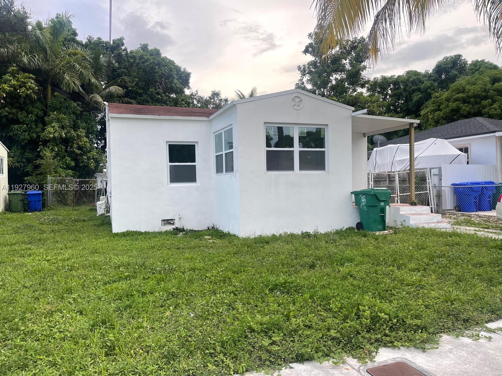 A small, white, single-story house with a flat roof and a front yard — 560 NW 53rd St, Miami FL 33127, MIAMI, FL