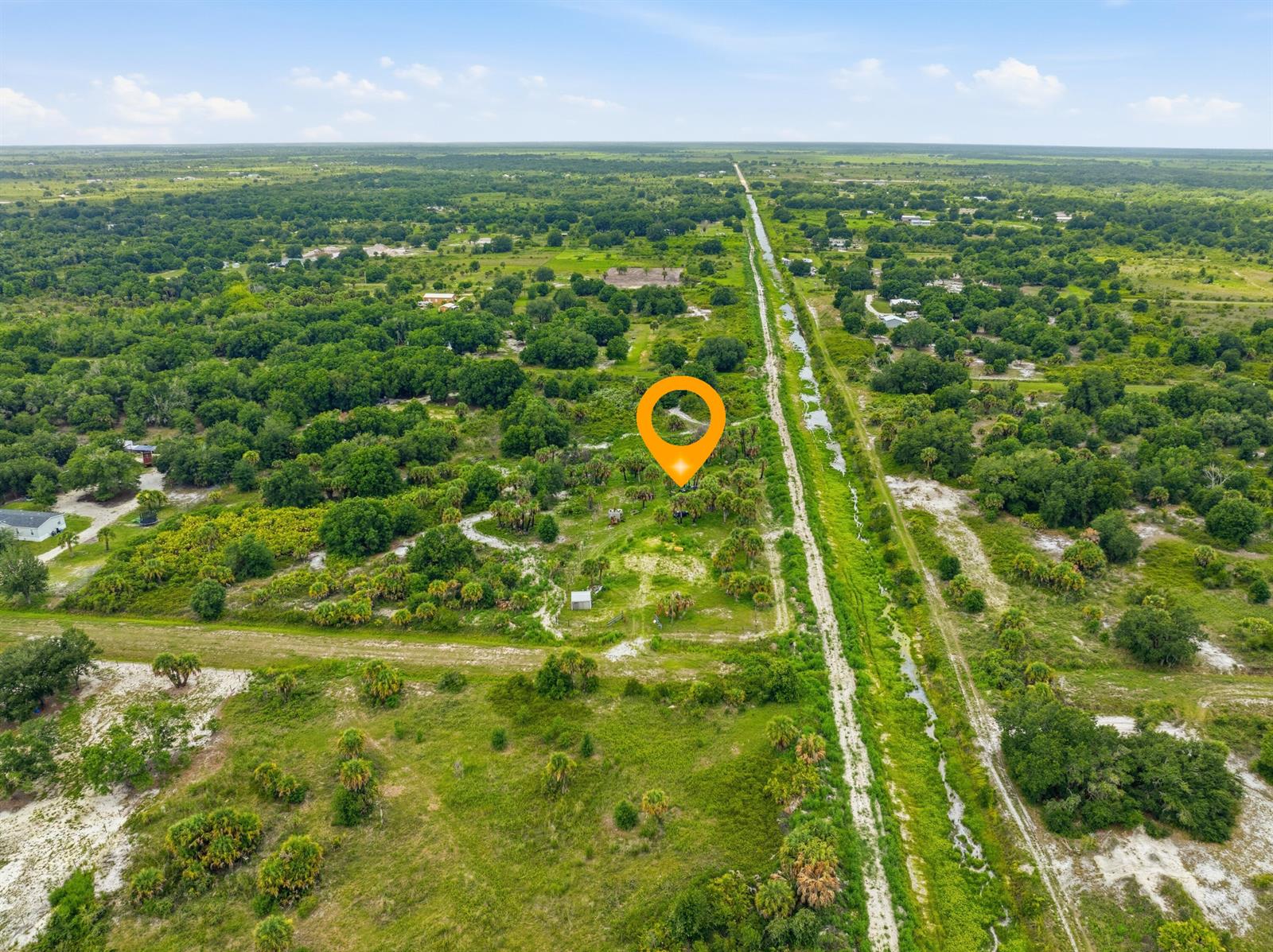 An aerial view shows a rural, wooded lot adjacent to a long, straight drainage canal — 19998 NW 270th Street, Okeechobee FL 34972, OKEECHOBEE, FL