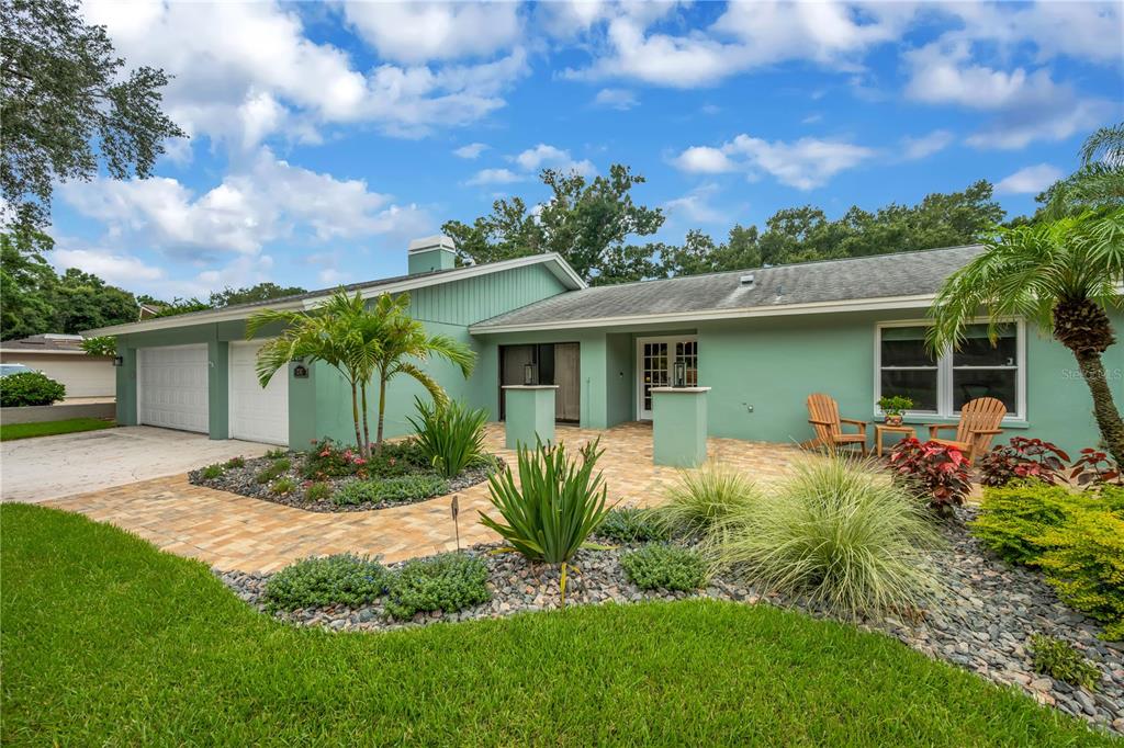 A light green single-story house features a paved walkway, a two-car garage, and landscaping — 2767 WESTCHESTER DRIVE N, CLEARWATER, FL