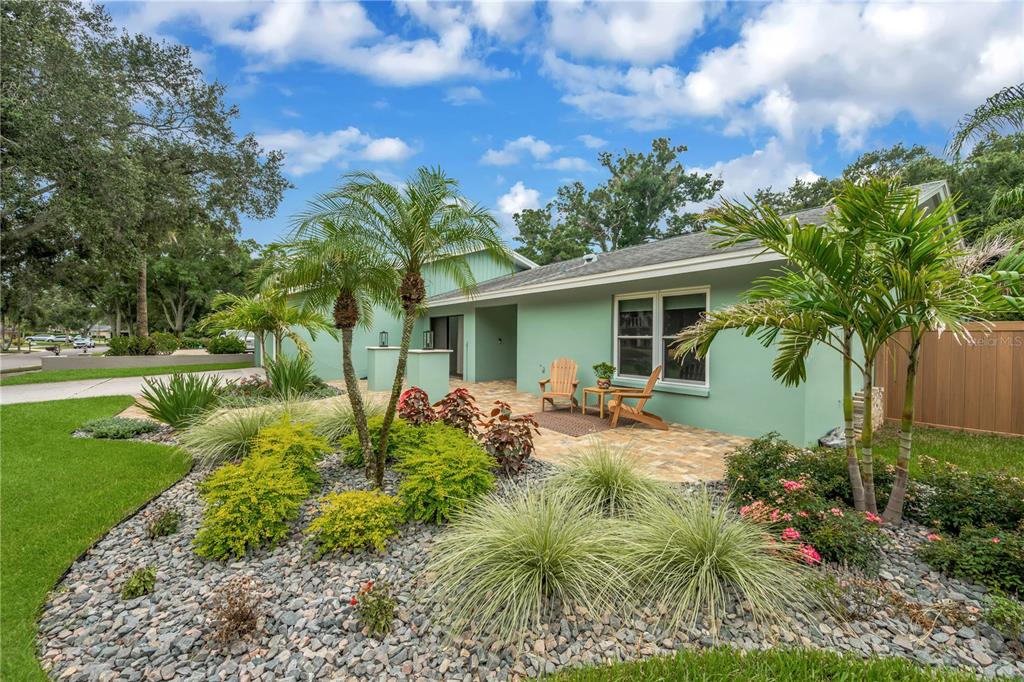 A light green house exterior features a stone patio, palm trees, and a rock garden — 2767 WESTCHESTER DRIVE N, CLEARWATER, FL