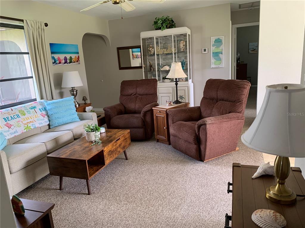 A living room features a beige sofa, two brown recliners, and a wooden coffee table — 18094 ACKERMAN AVENUE, PORT CHARLOTTE, FL
