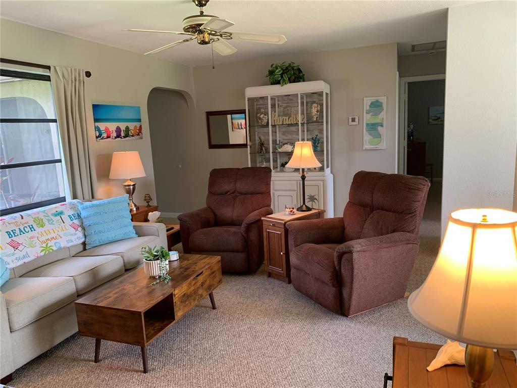 A living room features a sofa, two brown recliners, a coffee table, and a display cabinet — 18094 ACKERMAN AVENUE, PORT CHARLOTTE, FL