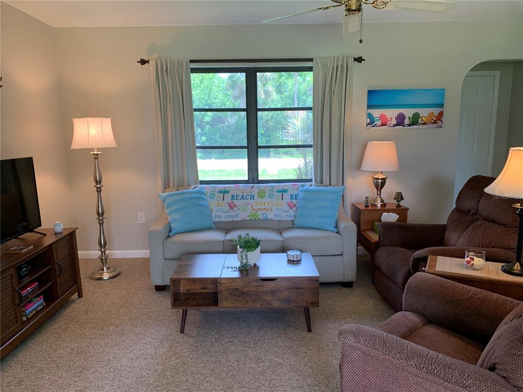 A living room features a beige sofa, brown armchairs, a coffee table, and a television — 18094 ACKERMAN AVENUE, PORT CHARLOTTE, FL