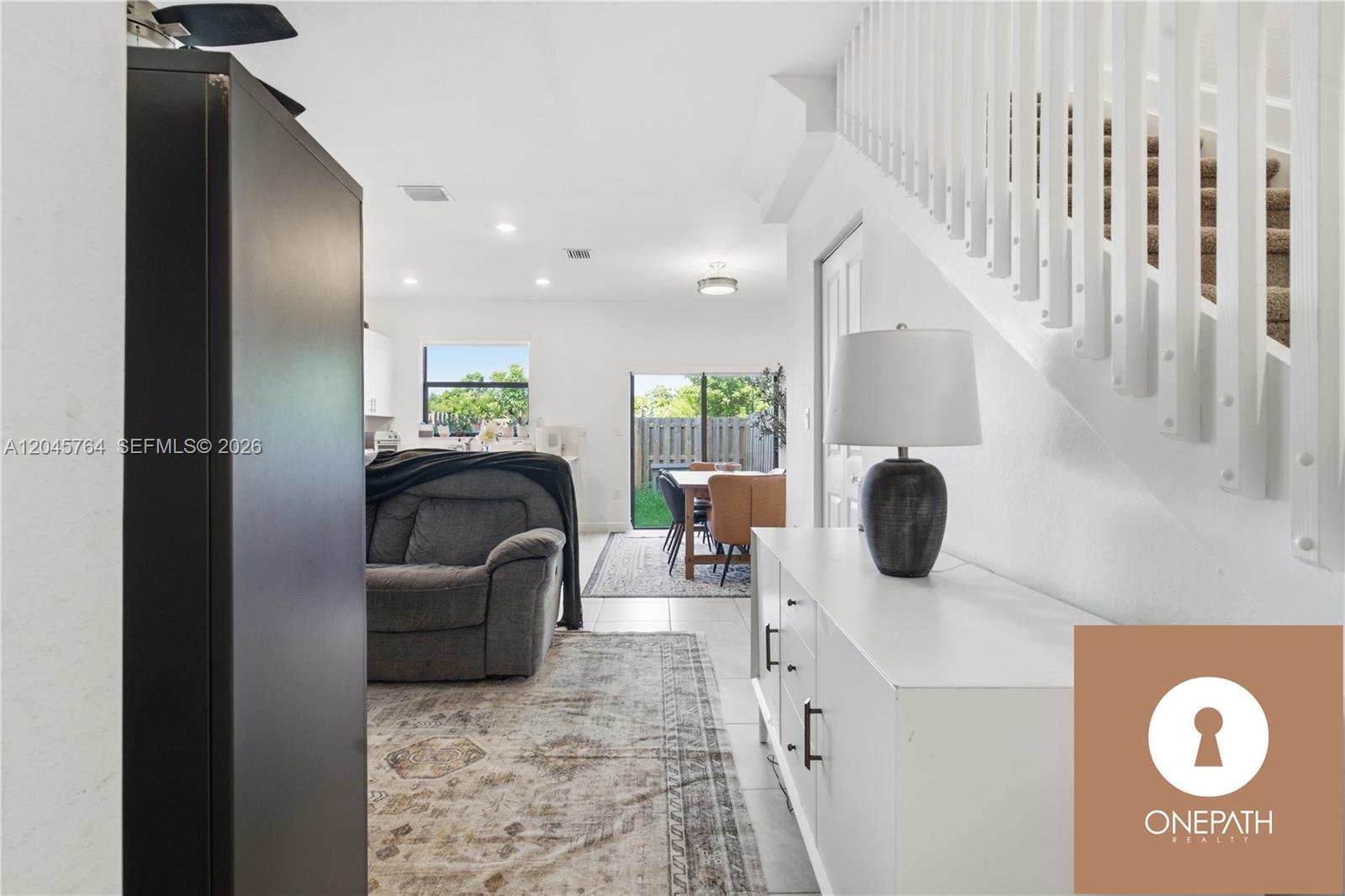 A white console table sits in a living area with a staircase and dining space — 23101 SW 99th Ave, Cutler Bay FL 33190, CUTLER BAY, FL