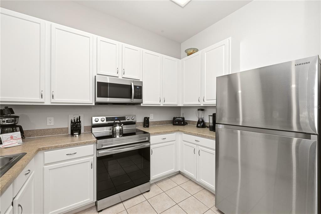 A kitchen with white cabinets, stainless steel appliances, and tan countertops — 102 RUM RUN UNIT 37-102, DAVENPORT, FL