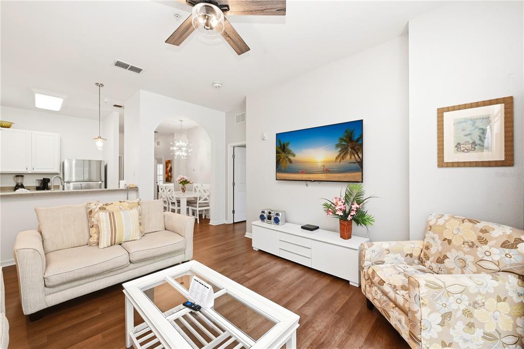 A living room features a beige sofa, floral armchair, white coffee table, and wall-mounted television — 102 RUM RUN UNIT 37-102, DAVENPORT, FL