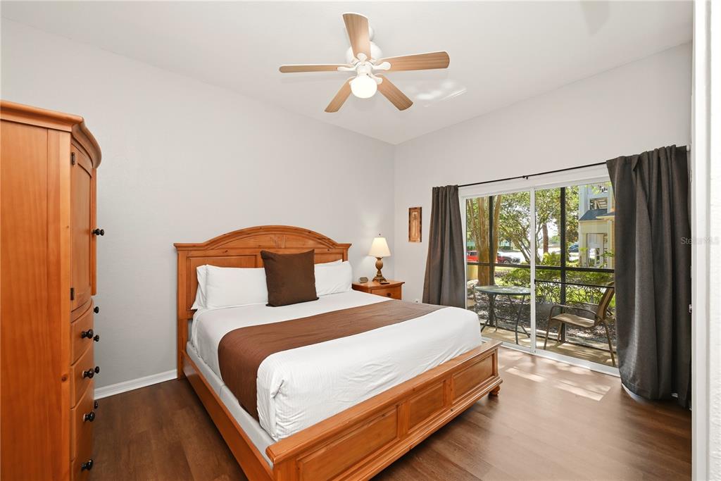 A bedroom features a wooden bed frame, a ceiling fan, and sliding doors to a patio — 102 RUM RUN UNIT 37-102, DAVENPORT, FL