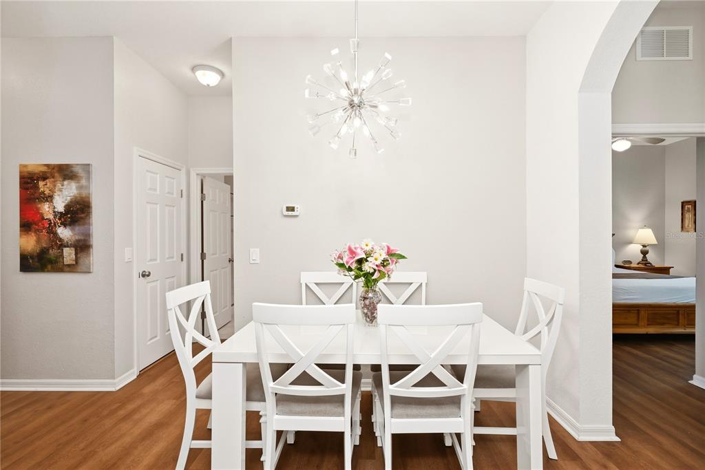 A dining room features a white table with four chairs, a modern chandelier, and wood flooring — 102 RUM RUN UNIT 37-102, DAVENPORT, FL