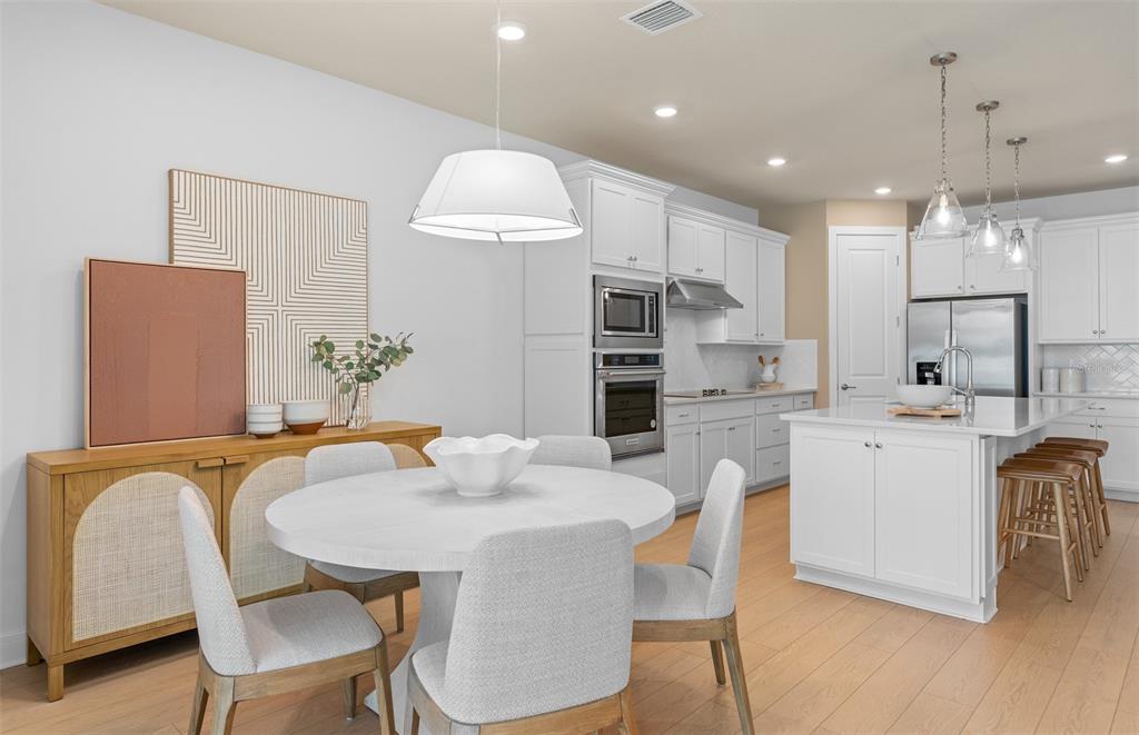 A bright, open-concept kitchen and dining area featuring white cabinetry, a round table, and island — 4806 FINLEY DRIVE, DAVENPORT, FL