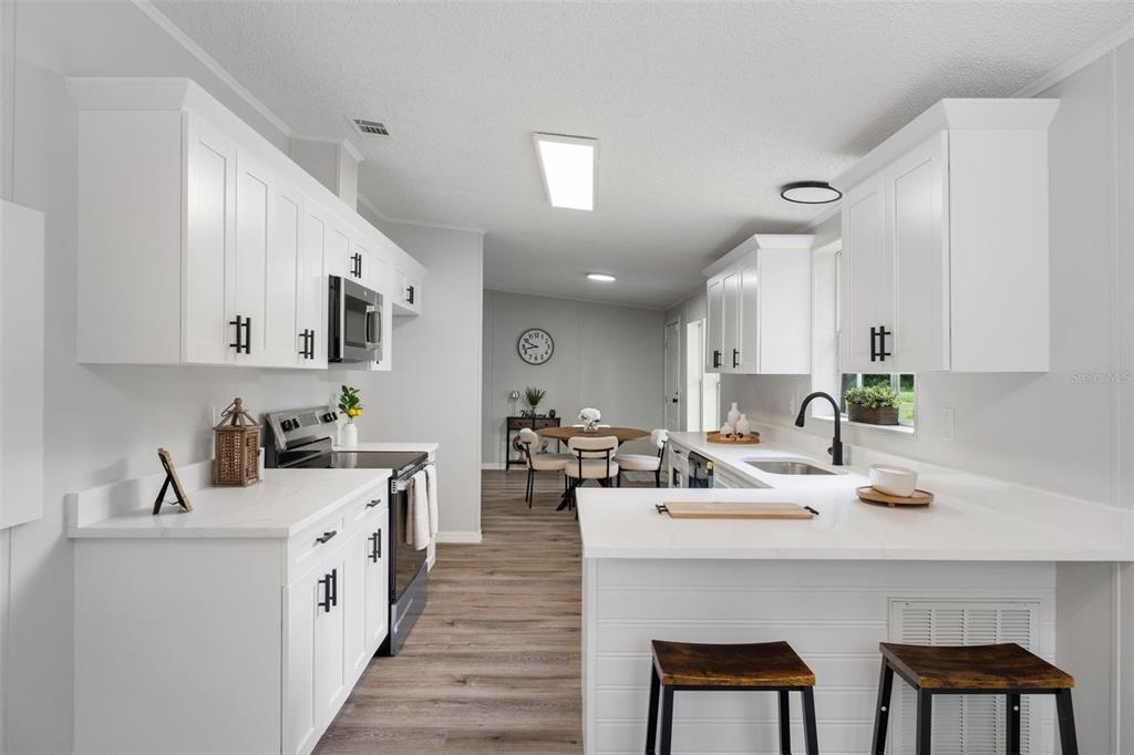 A bright kitchen features white cabinets, quartz countertops, black hardware, and a breakfast bar — 20645 STEWART ROAD, DADE CITY, FL