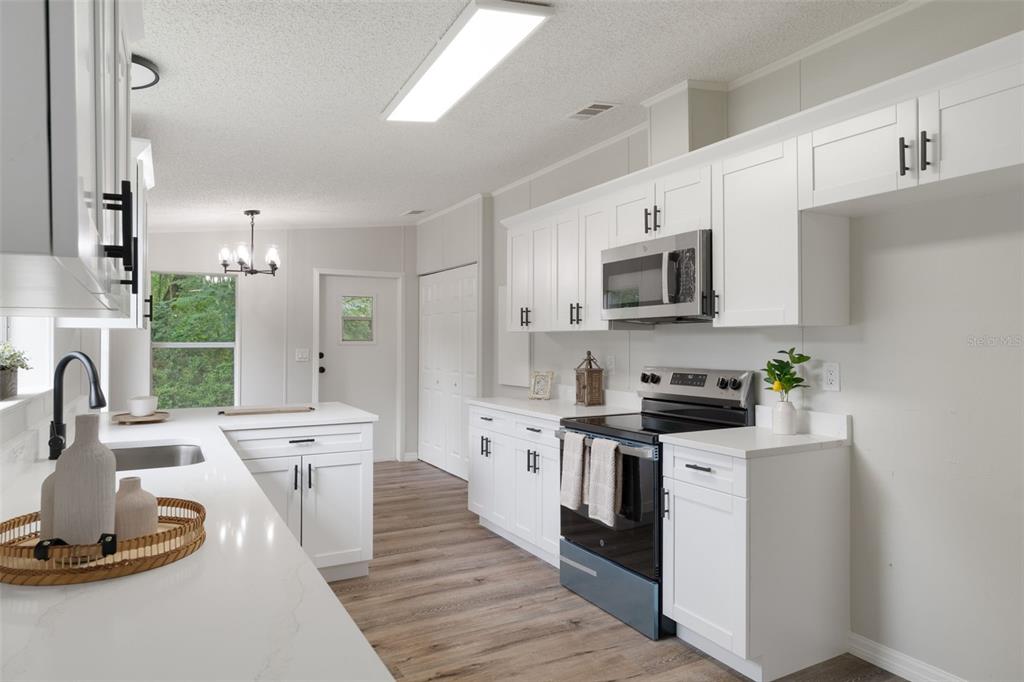 A kitchen features white cabinets, quartz countertops, stainless steel appliances, and wood-look flooring — 20645 STEWART ROAD, DADE CITY, FL