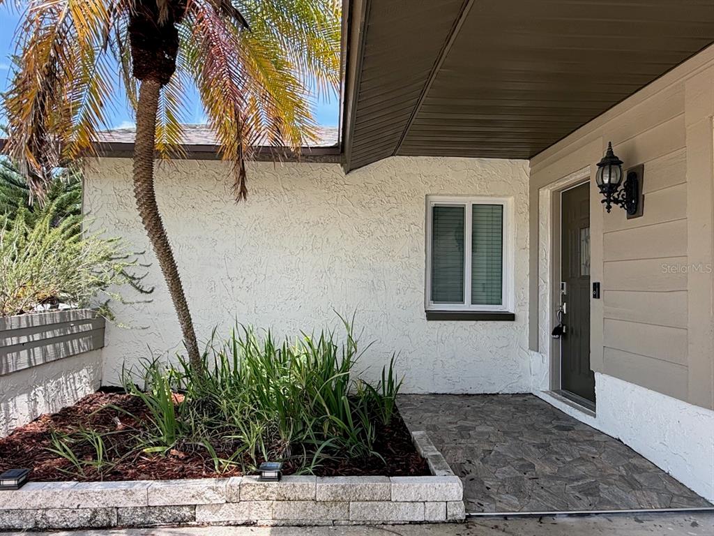 A small paved patio is enclosed by a horizontal wood privacy fence and lush greenery — 1583 REDWOOD AVENUE, DUNEDIN, FL