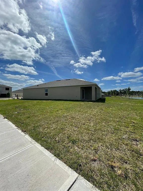 The exterior side and rear view of a single-story house with a grassy yard — 1246 RED HILL ROAD, DAVENPORT, FL