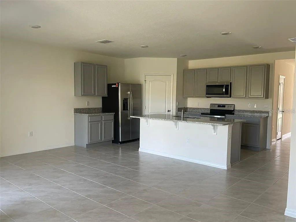 A kitchen with gray cabinets, granite countertops, stainless steel appliances, and tile flooring — 1246 RED HILL ROAD, DAVENPORT, FL