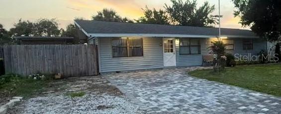 A single-story house with light gray siding and a paved driveway at sunset — 2545 STRATFORD DRIVE, COCOA, FL