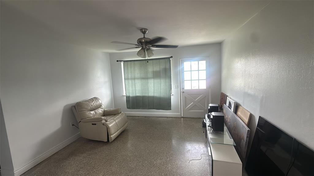 A living room features a beige recliner, a ceiling fan, a window, and a door — 2545 STRATFORD DRIVE, COCOA, FL