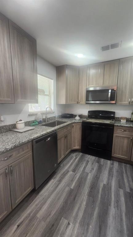 A kitchen with wood-look cabinets, granite countertops, stainless steel appliances, and gray wood-plank flooring — 2545 STRATFORD DRIVE, COCOA, FL