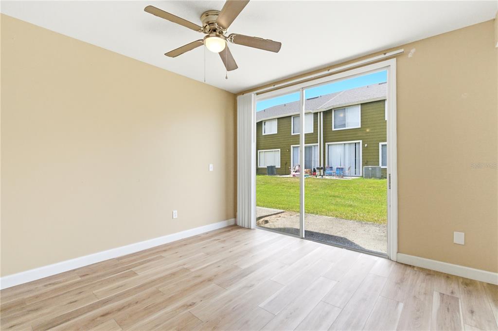 An empty room with light wood-look flooring, a ceiling fan, and sliding glass patio doors — 623 COCONUT PALM WAY UNIT 0, DAVENPORT, FL