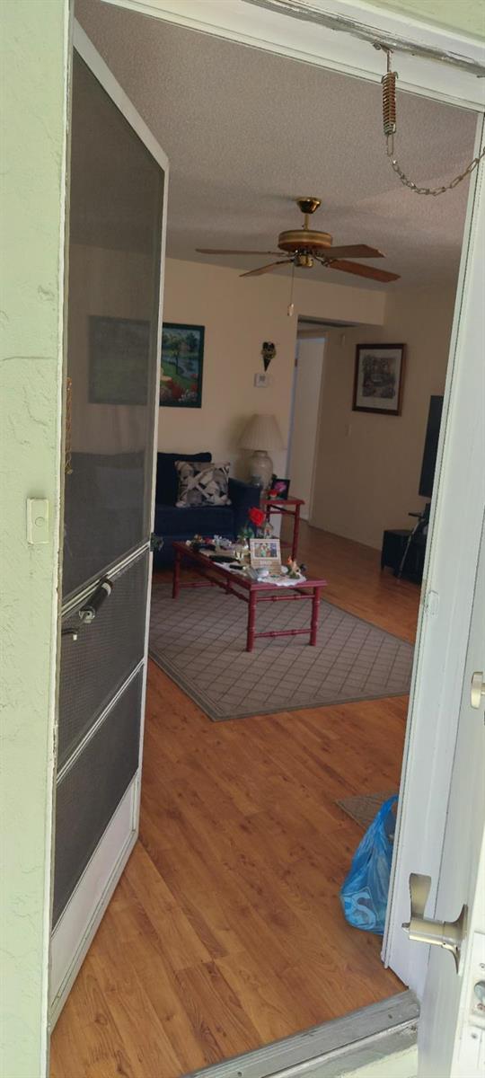 A view through an open screen door into a living room with wood-look flooring — 3100 Springdale Boulevard # 317, Palm Springs FL 33461, PALM SPRINGS, FL