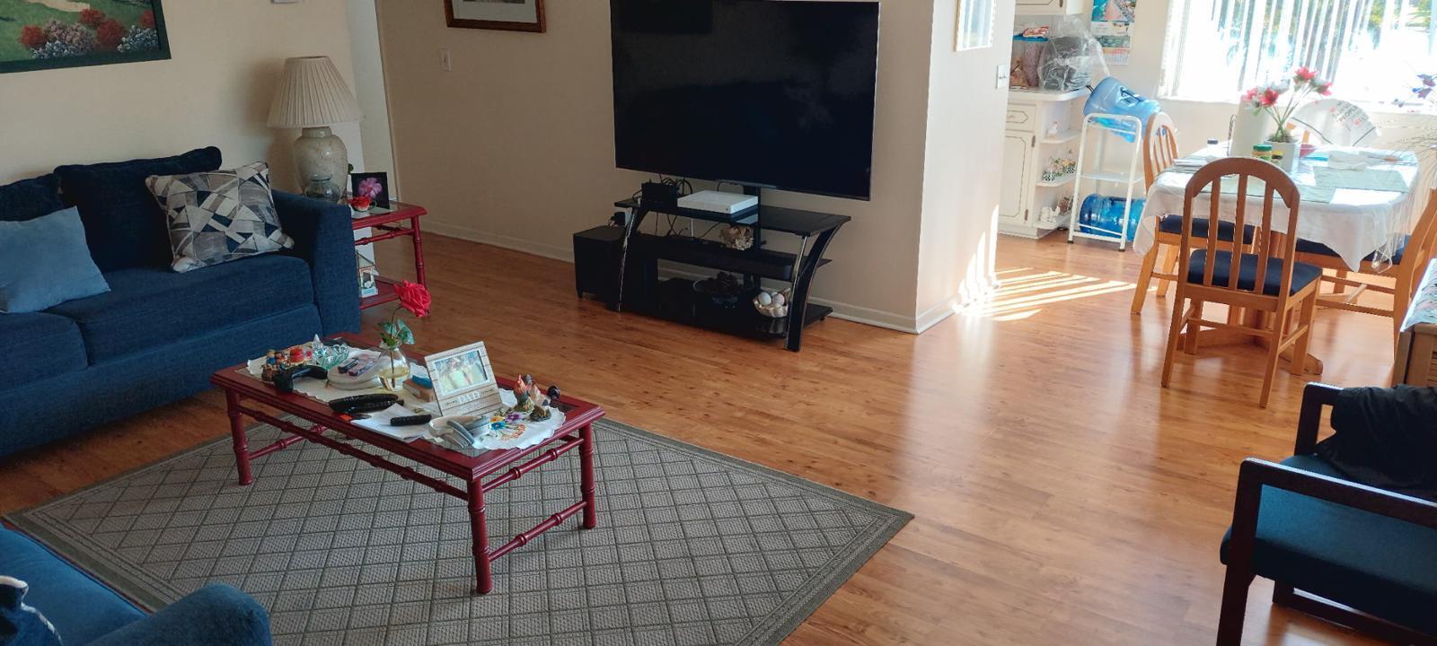 A living room with wood flooring, a blue sofa, a coffee table, and a dining area — 3100 Springdale Boulevard # 317, Palm Springs FL 33461, PALM SPRINGS, FL
