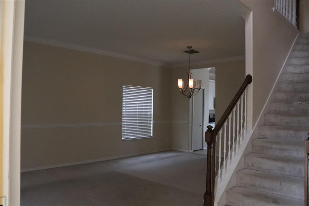 A carpeted room features a staircase with a wooden railing and a hanging chandelier — 14733 HARTFORD RUN DRIVE, ORLANDO, FL