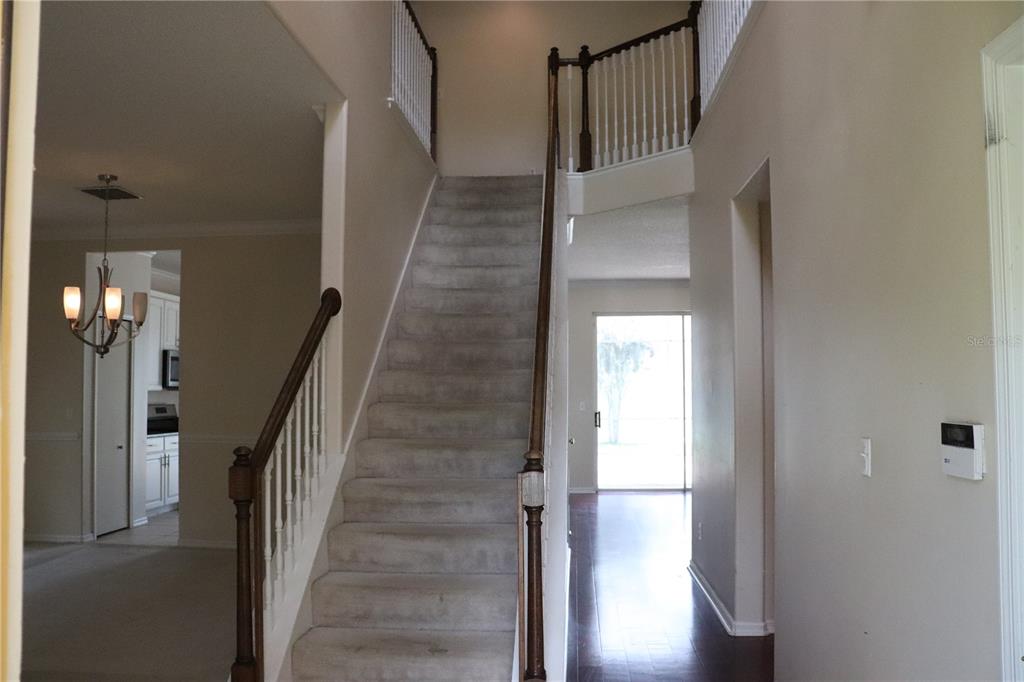An entryway features a carpeted staircase with wooden railings leading to a second-floor landing — 14733 HARTFORD RUN DRIVE, ORLANDO, FL