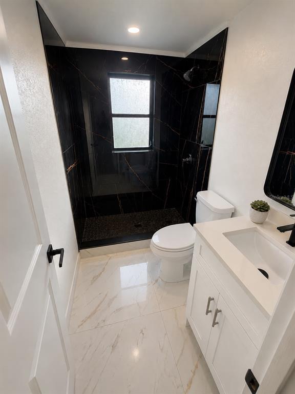 A bathroom features a black marble-tiled shower, white vanity, and light-colored marble-look floor tiles — 7035 PALISADE DRIVE, PORT RICHEY, FL
