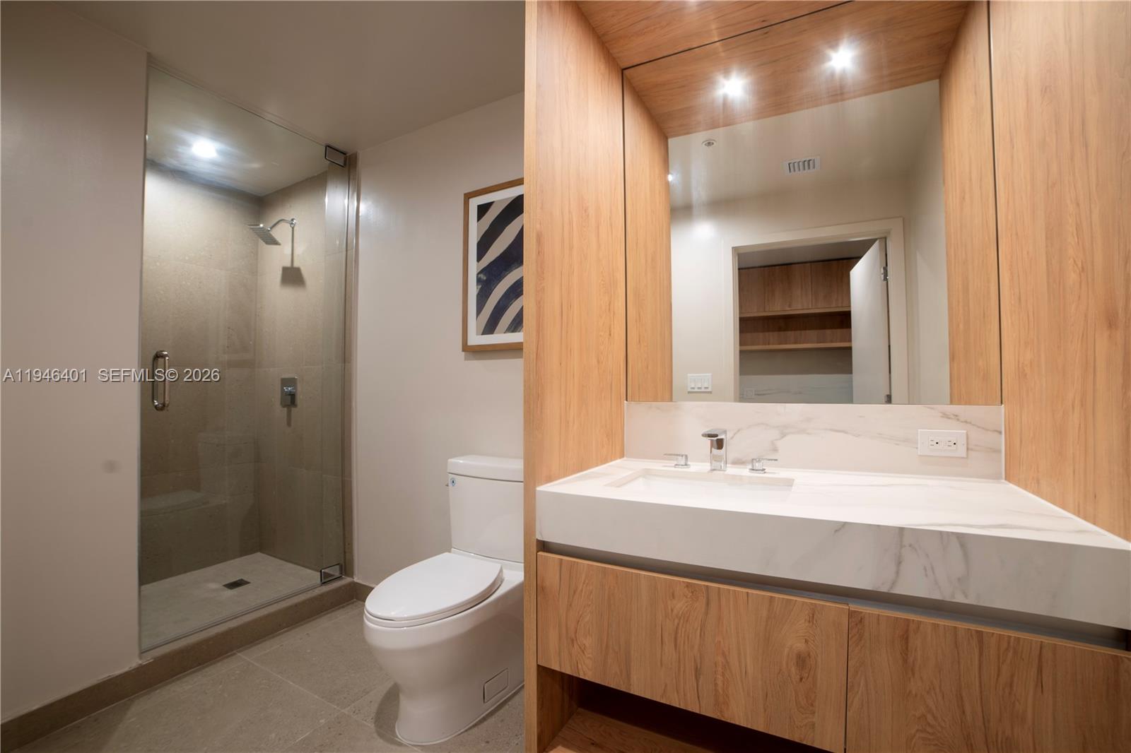 A modern bathroom features a glass-enclosed shower, a white toilet, and a wood-vanity with marble — 11 NE 6TH # 1908, Miami FL 33132, MIAMI, FL
