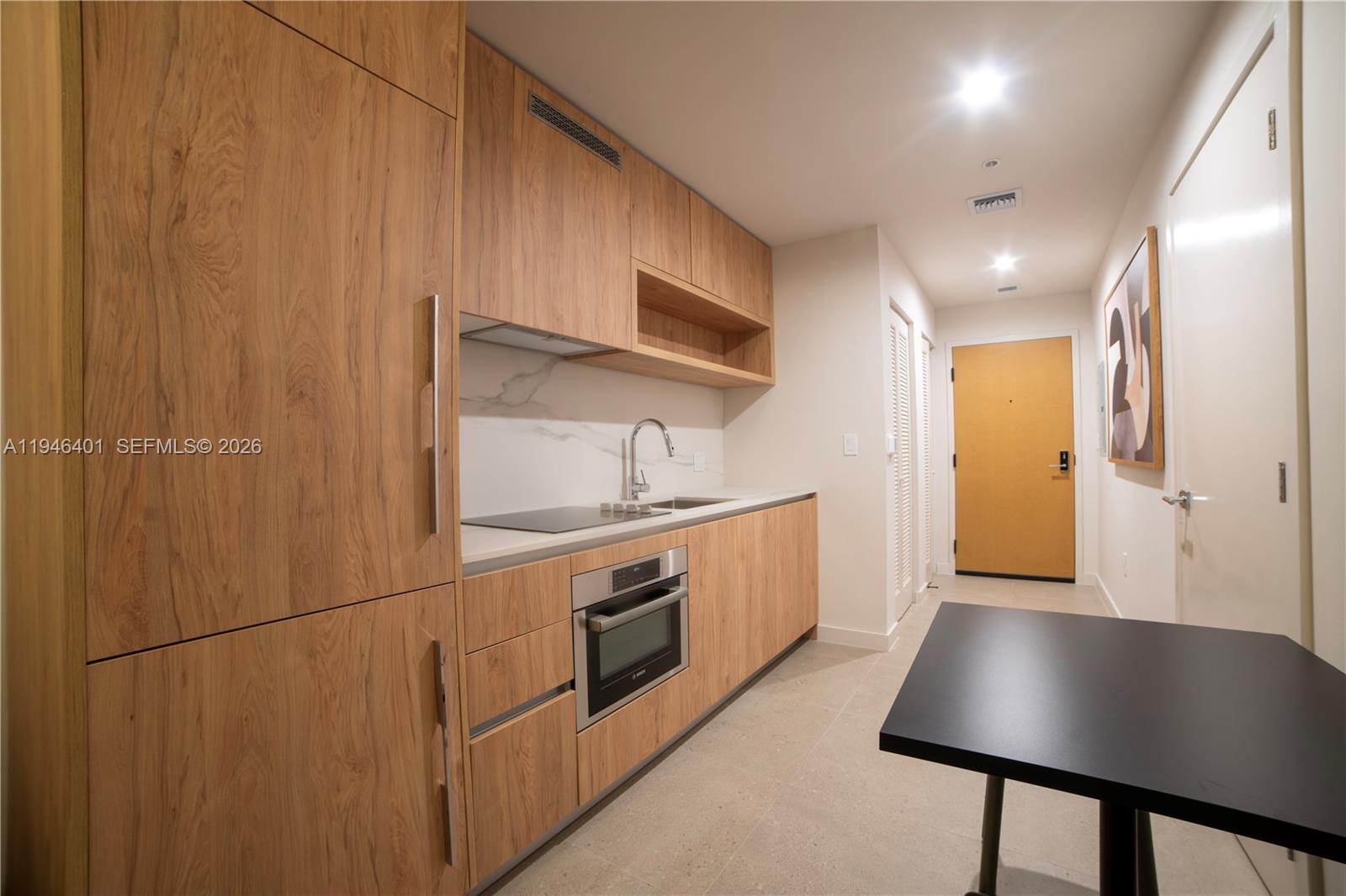 A modern kitchen features wood-grain cabinetry, a marble backsplash, and a built-in oven — 11 NE 6TH # 1908, Miami FL 33132, MIAMI, FL