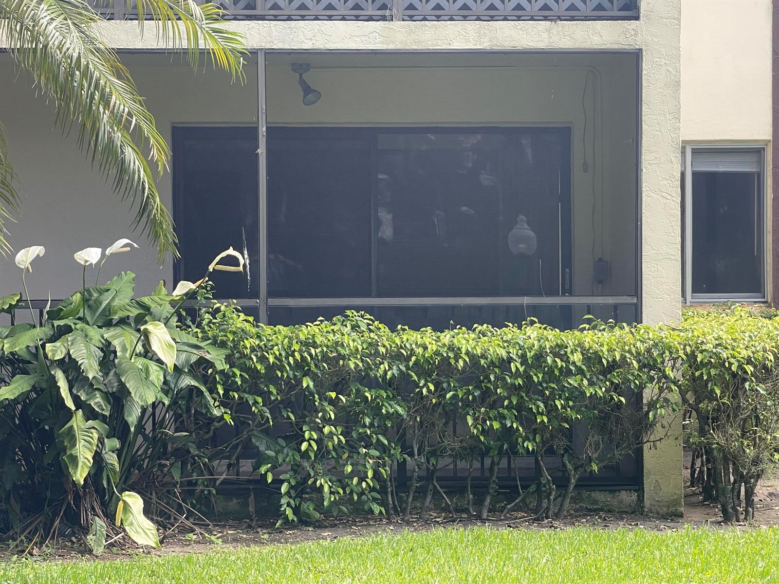 A ground-floor patio with a screened enclosure, sliding glass doors, and surrounding landscaping — 4857 Sable Pine Circle # B1, West Palm Beach FL 33417, WEST PALM BEACH, FL