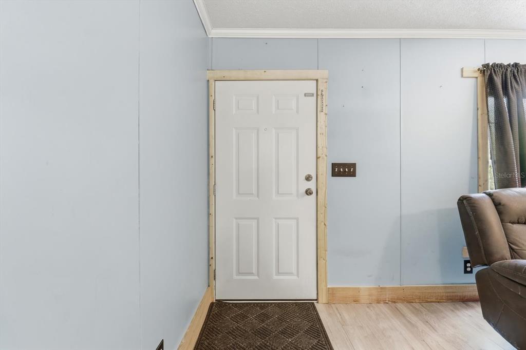 A room with light blue walls, a white door with unfinished trim, and wood-look flooring — 10382 W KILLARNEY STREET, CRYSTAL RIVER, FL