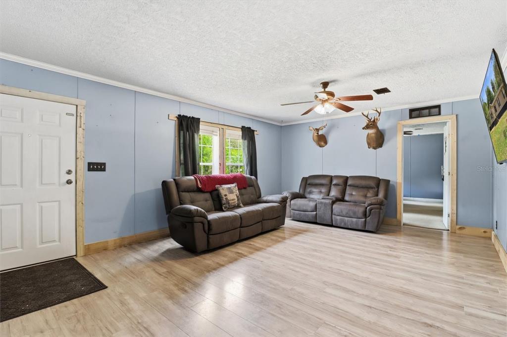 A living room features light blue walls, wood-look flooring, two brown sofas, and deer mounts — 10382 W KILLARNEY STREET, CRYSTAL RIVER, FL