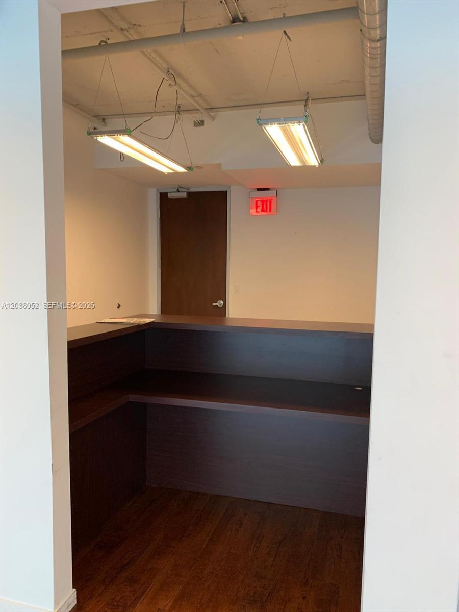 A small room features a dark wood reception desk, wood flooring, and exposed ceiling fixtures — 14 NE 1st Ave # Q, Miami FL 33132, MIAMI, FL