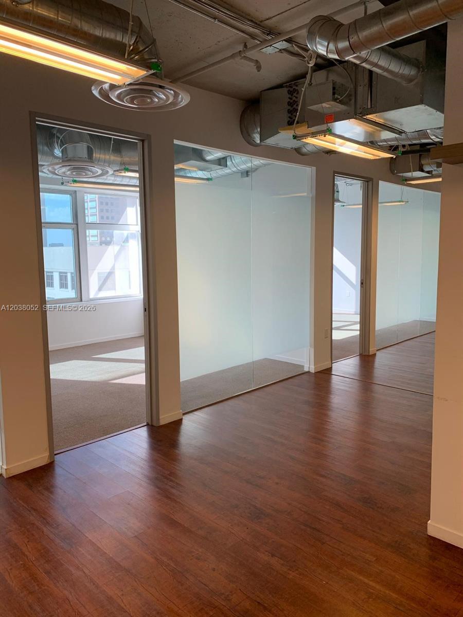An office interior features wood-look flooring, glass-walled partitions, and exposed ceiling ductwork — 14 NE 1st Ave # Q, Miami FL 33132, MIAMI, FL