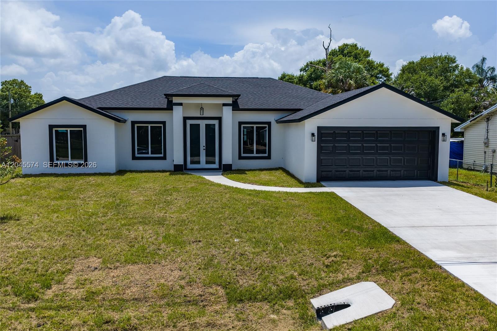A single-story house with white stucco walls, a black roof, and a two-car garage — 5203 Birch Dr, Fort Pierce FL 34945, FORT PIERCE, FL