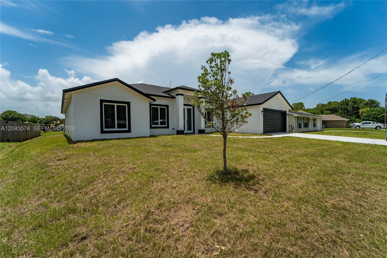 A white single-story house with a black roof and garage sits on a grassy lot — 5203 Birch Dr, Fort Pierce FL 34945, FORT PIERCE, FL