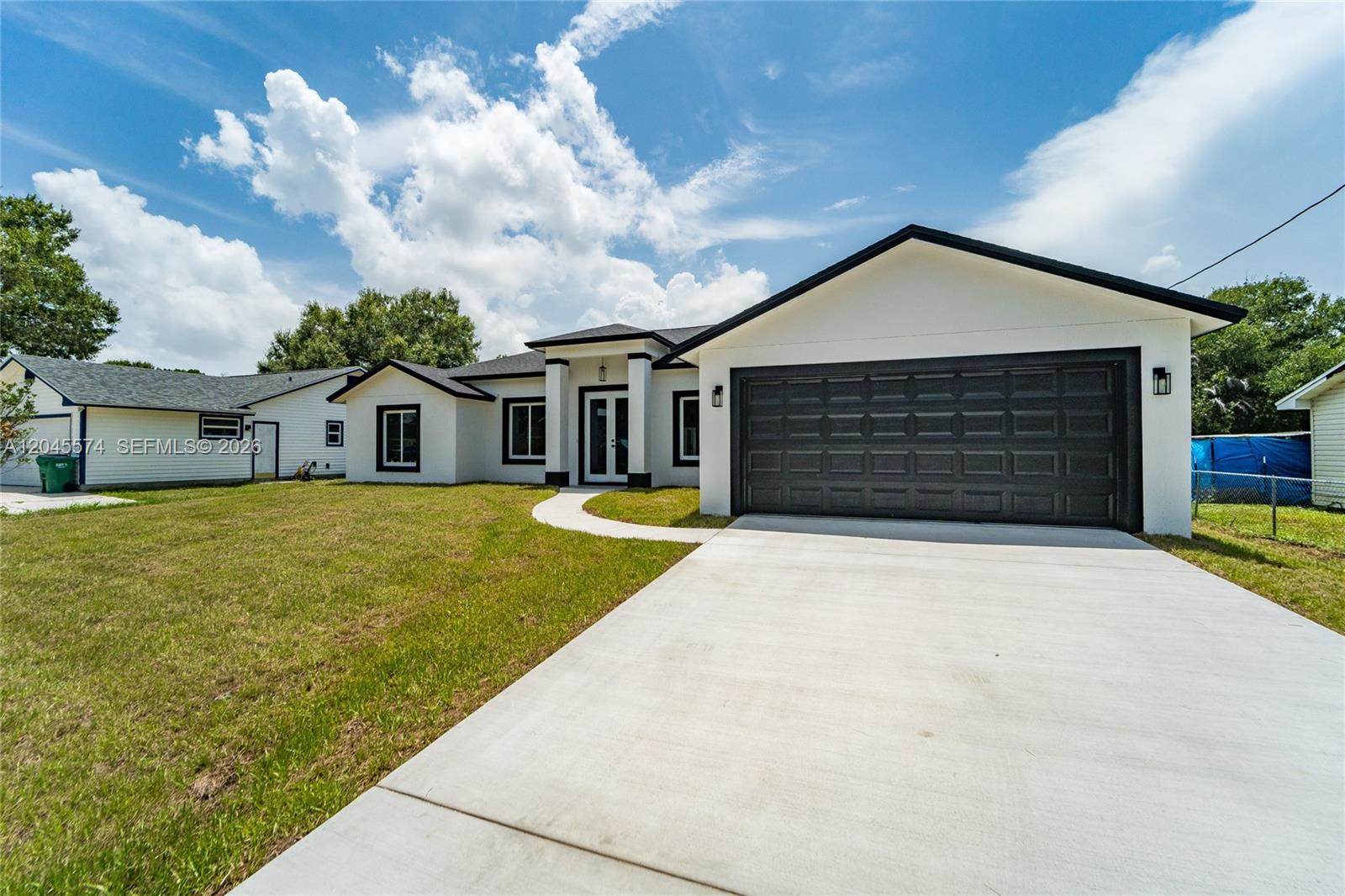 A modern white house with black trim and a large garage sits on a lawn — 5203 Birch Dr, Fort Pierce FL 34945, FORT PIERCE, FL