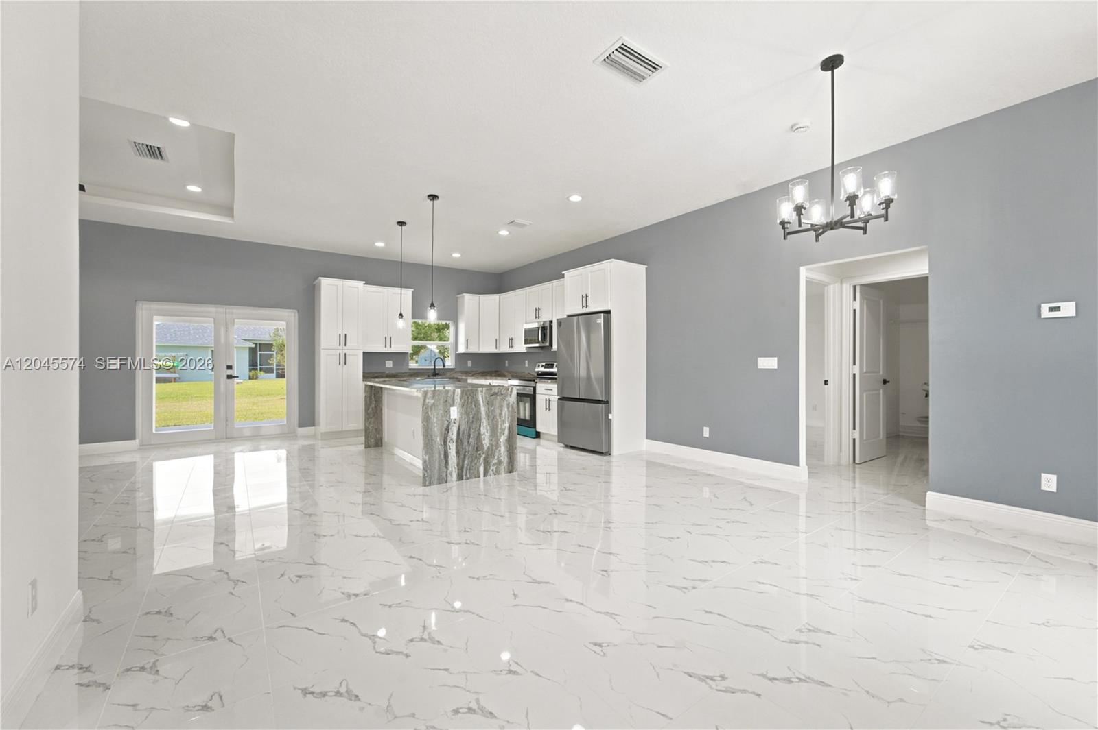 A modern kitchen features white cabinets, a marble-topped island, and glossy white tile flooring — 5203 Birch Dr, Fort Pierce FL 34945, FORT PIERCE, FL