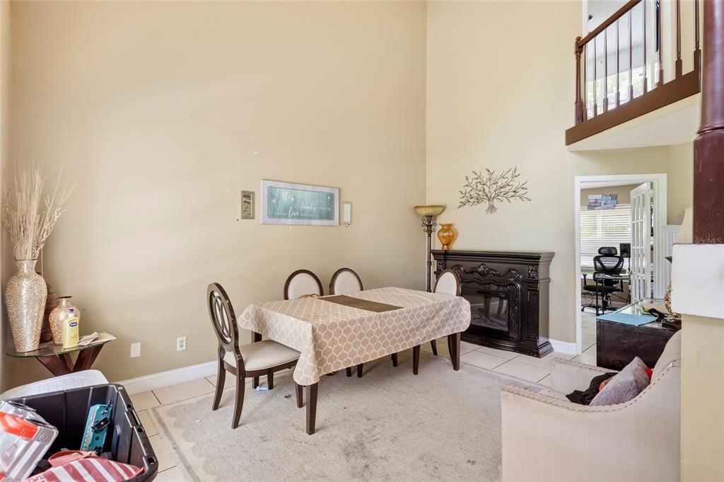 A dining area features a table, chairs, a fireplace, and a high ceiling — 1071 SUMMER LAKES DRIVE, ORLANDO, FL