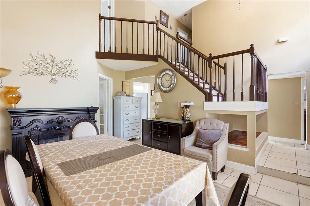 A dining area features a staircase with dark wood railings and a large wall clock — 1071 SUMMER LAKES DRIVE, ORLANDO, FL