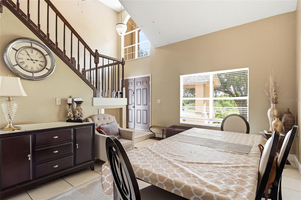 A dining area features a staircase, a large wall clock, and a window with blinds — 1071 SUMMER LAKES DRIVE, ORLANDO, FL