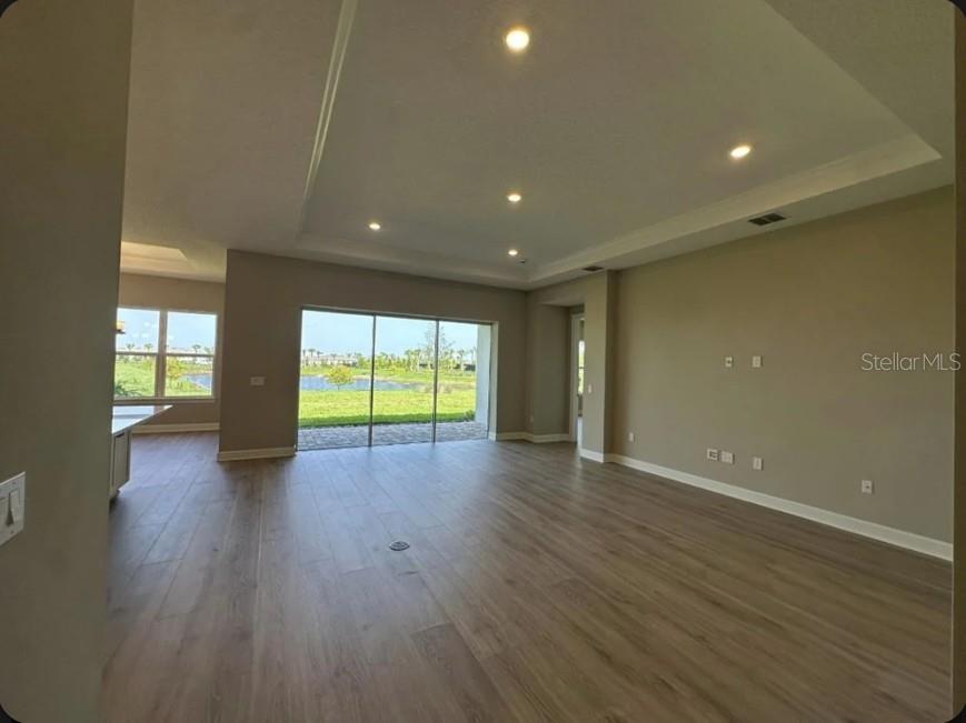 An open-concept living area features light wood-look flooring, recessed lighting, and sliding glass doors — 998 TASSLEFLOWER TRAIL, ST CLOUD, FL