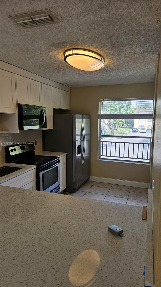 A kitchen features white cabinets, stainless steel appliances, tile flooring, and a window with blinds — 8039 SW 21st Ct # 8039, Miramar FL 33025, MIRAMAR, FL