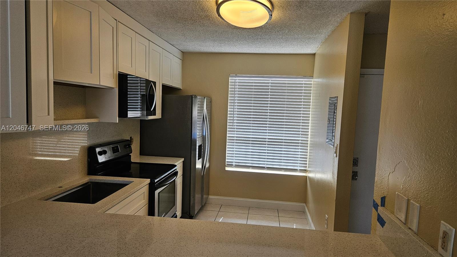 A kitchen features white cabinets, stainless steel appliances, a window with blinds, and tile flooring — 8039 SW 21st Ct # 8039, Miramar FL 33025, MIRAMAR, FL