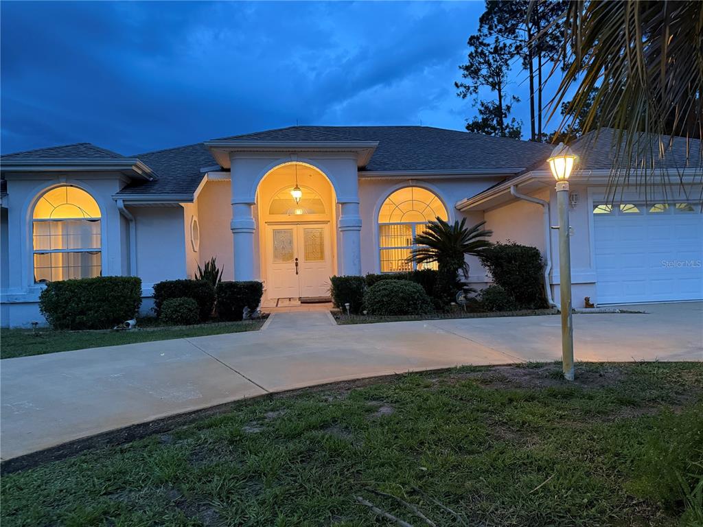A single-story house with a white stucco exterior, arched windows, and a double-door entryway — 78 BARRINGTON DRIVE, PALM COAST, FL
