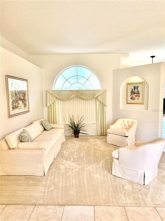 A living room features a beige sofa, two armchairs, and a large arched window — 78 BARRINGTON DRIVE, PALM COAST, FL