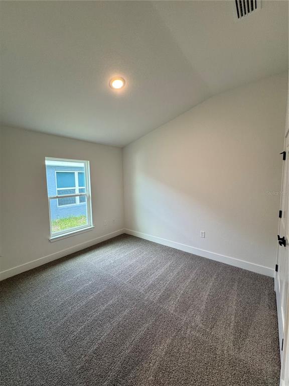 An empty bedroom features gray carpet, white walls, a single window, and a vaulted ceiling — 2667 AVERLAND LOOP, NORTH PORT, FL