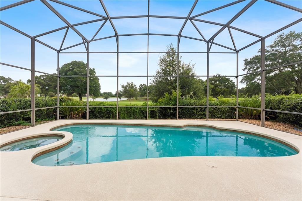 A screened-in swimming pool and spa overlook a golf course and pond — 1240 GLENCREST DRIVE, LAKE MARY, FL